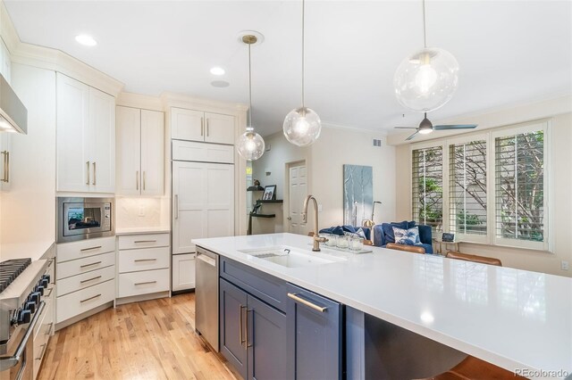 581 Garfield St, Denver, CO 80206 - kitchen featuring appliances with stainless steel finishes, light countertops, light wood-style floors, hanging light fixtures, and crown molding