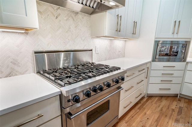 581 Garfield St, Denver, CO 80206 - kitchen featuring appliances with stainless steel finishes, premium range hood, tasteful backsplash, and light countertops
