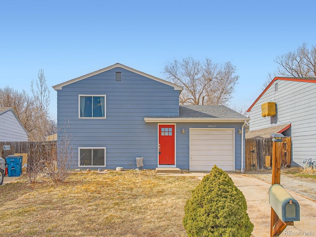 split level home with a garage, driveway, a front yard, and fence