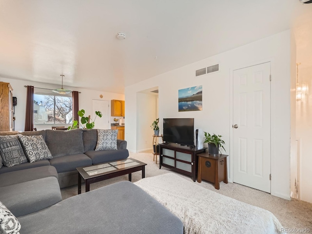 living area featuring baseboards, visible vents, and light colored carpet