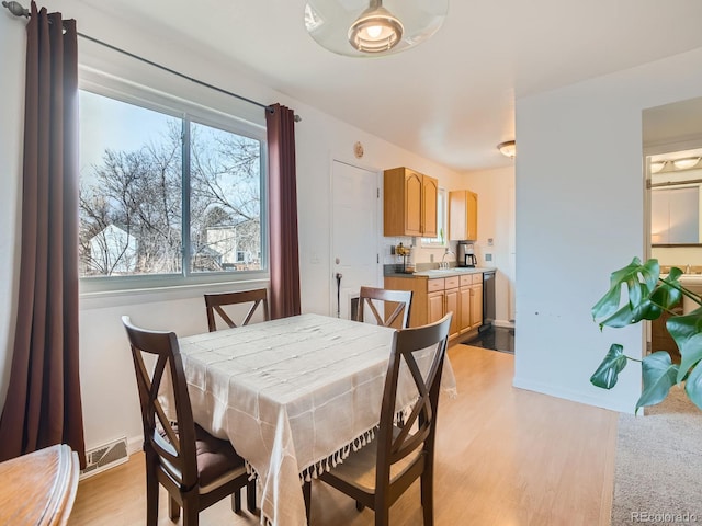 dining room featuring baseboards, visible vents, and light wood-style floors