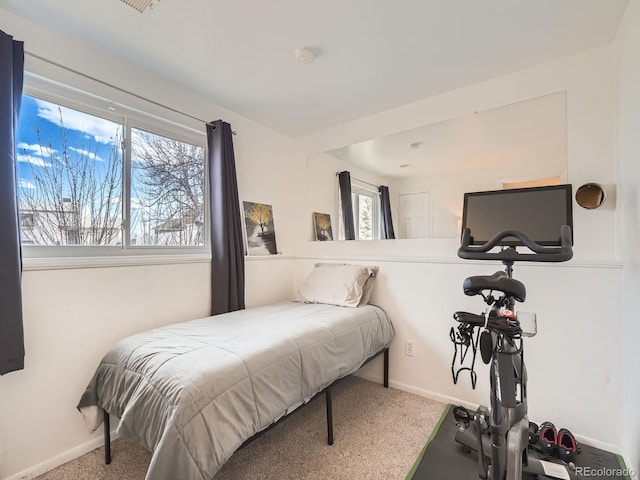 carpeted bedroom featuring multiple windows and baseboards