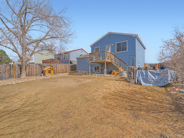 rear view of property with a fenced backyard, stairway, and a yard