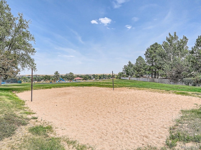 surrounding community with volleyball court, a lawn, and fence