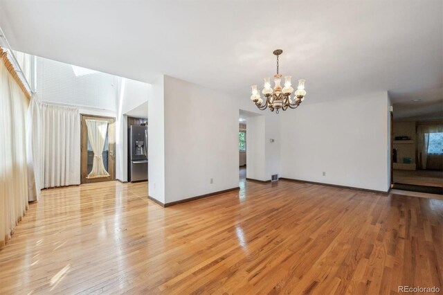4855 S Joplin St, Aurora, CO 80015 - unfurnished living room with a chandelier, light wood-style flooring, healthy amount of natural light, and baseboards