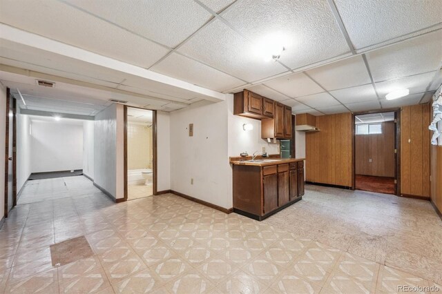 4855 S Joplin St, Aurora, CO 80015 - kitchen featuring light floors, a drop ceiling, baseboards, a sink, and wood walls