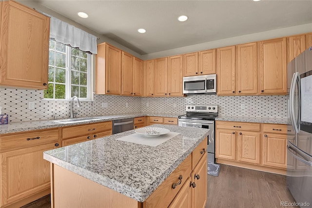 kitchen featuring a center island, sink, dark hardwood / wood-style floors, appliances with stainless steel finishes, and light stone counters