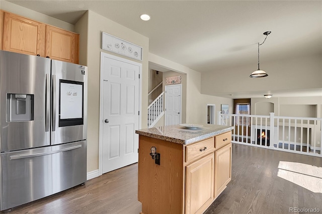 kitchen featuring a center island, light brown cabinets, hanging light fixtures, dark hardwood / wood-style flooring, and stainless steel fridge