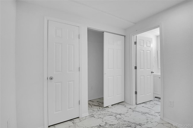 unfurnished bedroom with marble finish floor, a closet, and baseboards