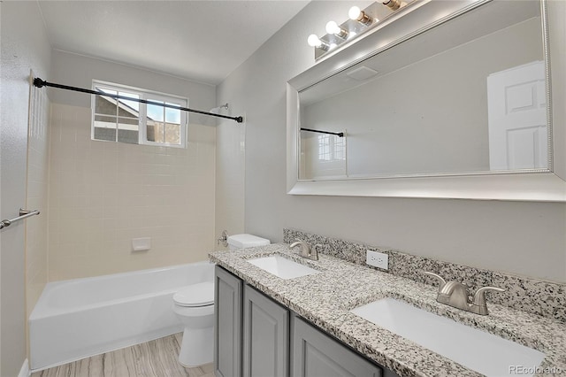 full bathroom featuring hardwood / wood-style flooring, vanity, toilet, and tiled shower / bath