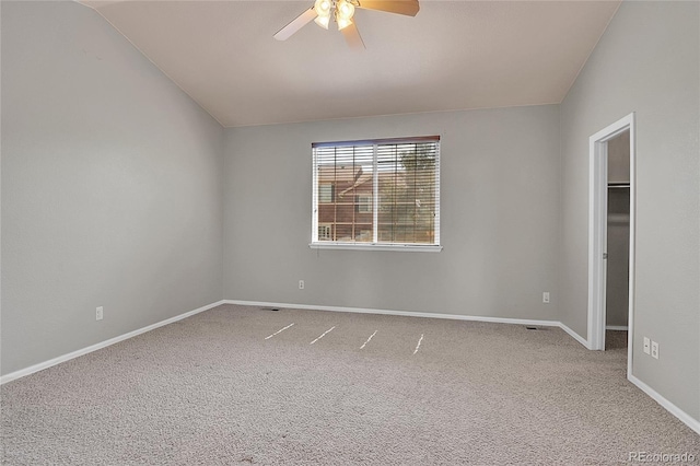 unfurnished bedroom featuring carpet floors, a spacious closet, baseboards, and vaulted ceiling