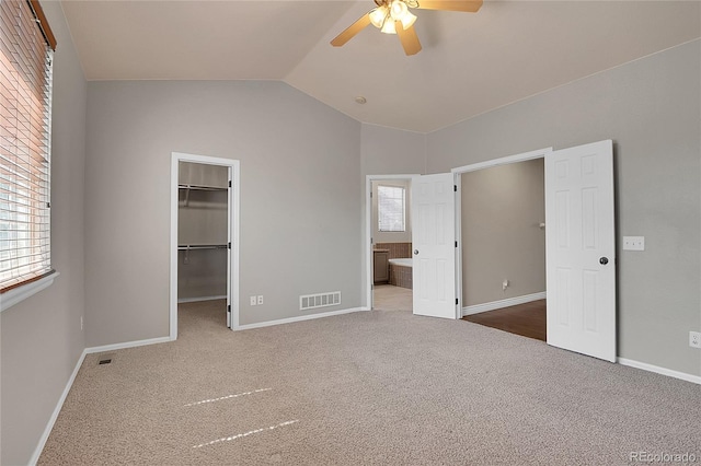 unfurnished bedroom with ceiling fan, a spacious closet, carpet floors, and lofted ceiling