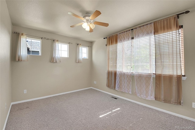 carpeted empty room with baseboards, visible vents, ceiling fan, and a textured ceiling