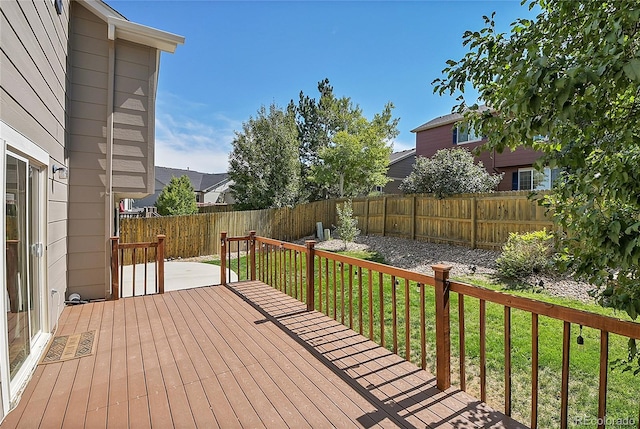 wooden terrace with a fenced backyard and a lawn