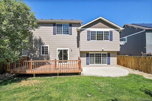 back of property with a deck, a patio, a lawn, and fence