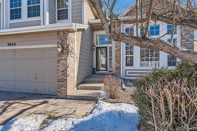 snow covered property entrance featuring a garage