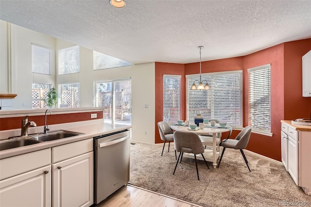 kitchen featuring dishwasher, sink, hanging light fixtures, and white cabinets