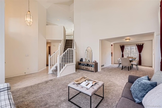 carpeted living room with a towering ceiling and a chandelier