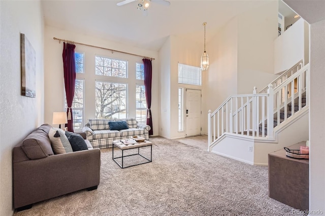 living room featuring a towering ceiling, ceiling fan, and carpet flooring