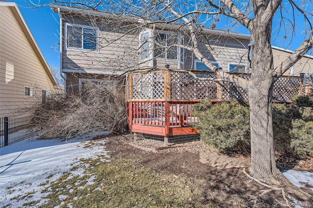 snow covered back of property featuring a deck