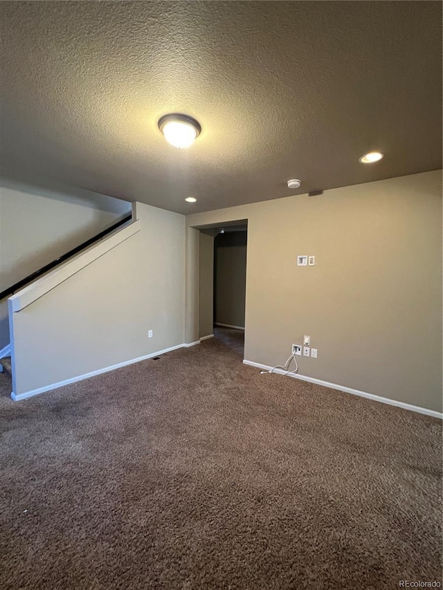 basement featuring dark carpet and a textured ceiling