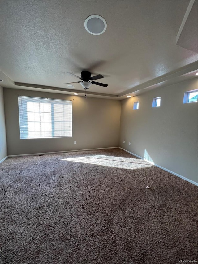 carpeted spare room with a textured ceiling, ceiling fan, and a healthy amount of sunlight