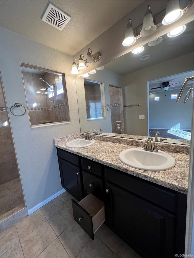 bathroom featuring vanity, tile patterned floors, ceiling fan, a textured ceiling, and a tile shower