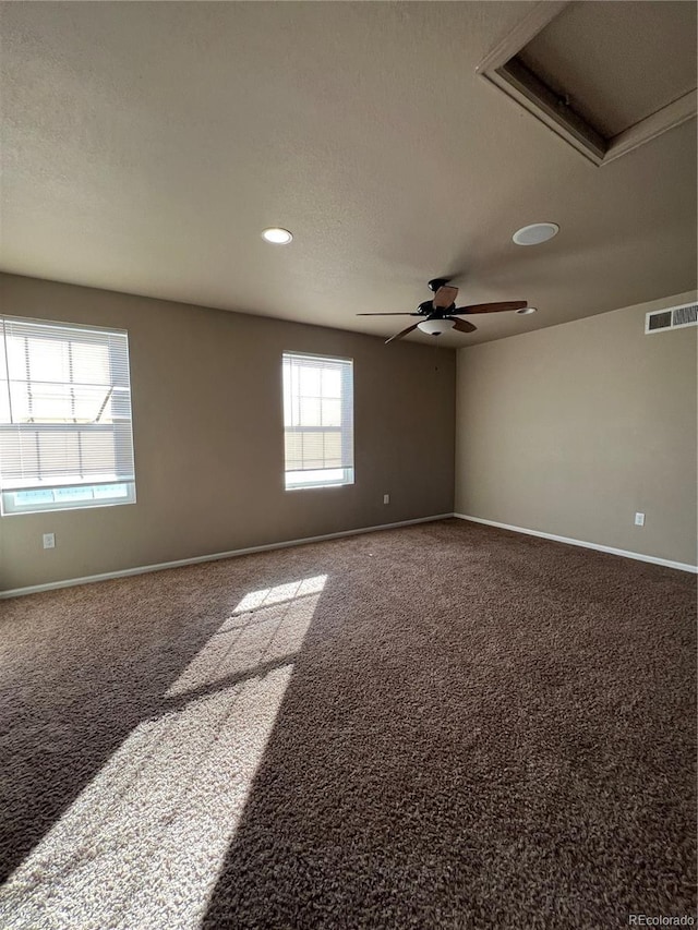 empty room featuring plenty of natural light, ceiling fan, carpet floors, and a textured ceiling