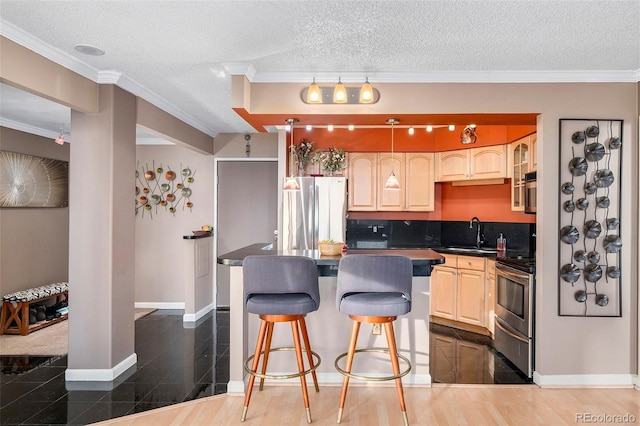 kitchen with dark countertops, light brown cabinets, appliances with stainless steel finishes, and ornamental molding