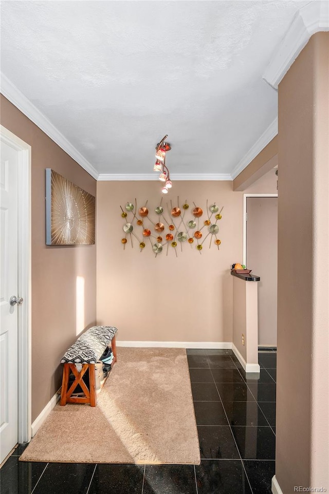 hallway featuring dark tile patterned floors, crown molding, and baseboards