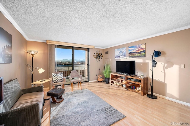 living area with crown molding, wood finished floors, baseboards, and a textured ceiling