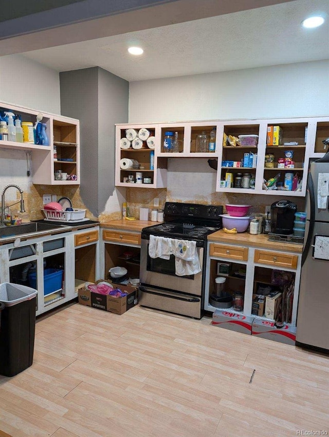 kitchen with appliances with stainless steel finishes, sink, light wood-type flooring, and backsplash