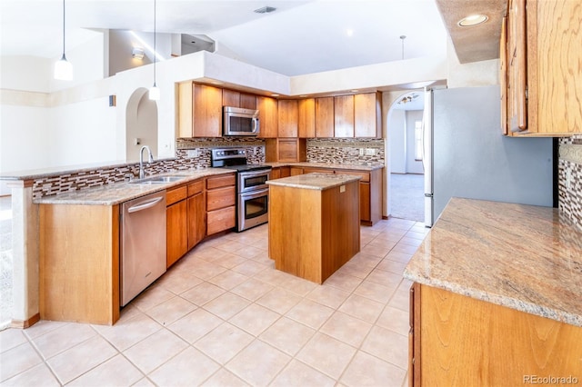 kitchen with hanging light fixtures, sink, light tile patterned floors, a kitchen island, and stainless steel appliances