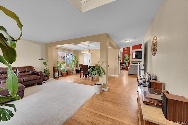 living room with lofted ceiling, a chandelier, and light hardwood / wood-style flooring