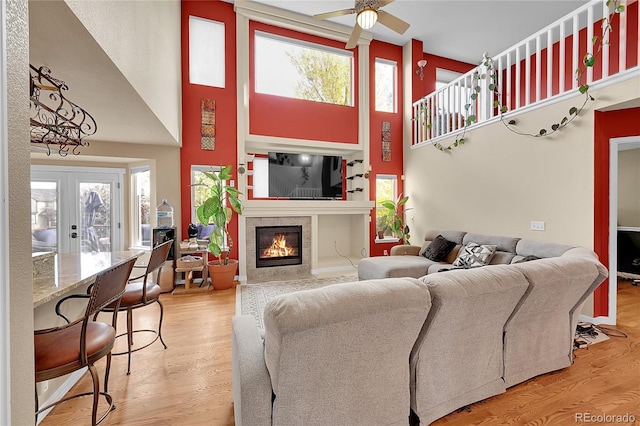 living room with a towering ceiling, hardwood / wood-style floors, a wealth of natural light, and ceiling fan