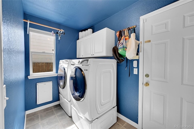 laundry room with light tile patterned flooring, washer and dryer, and cabinets