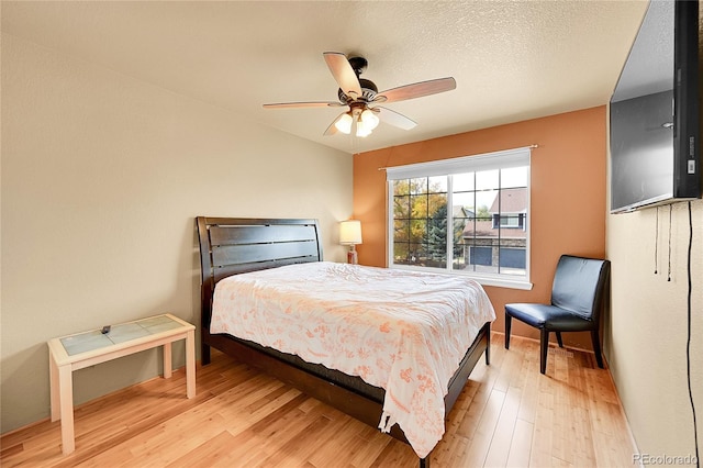 bedroom featuring light hardwood / wood-style floors, a textured ceiling, and ceiling fan