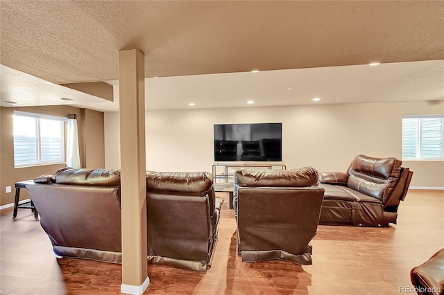 living room featuring wood-type flooring, a textured ceiling, and a wealth of natural light