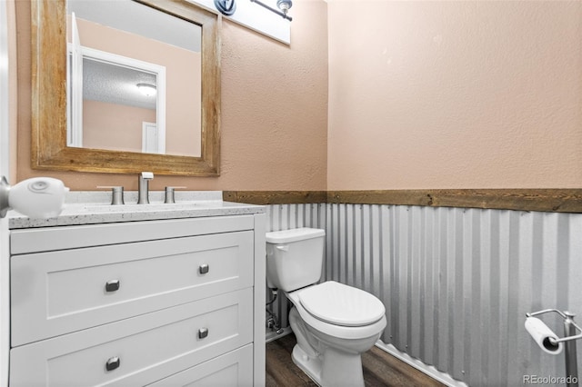 bathroom with vanity, wood-type flooring, a textured ceiling, and toilet