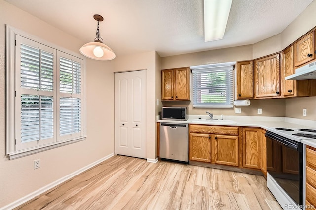 1648 S Cole St Unit A2, Lakewood, CO 80228 - kitchen with stainless steel appliances, a sink, light wood-style floors, brown cabinets, and light countertops