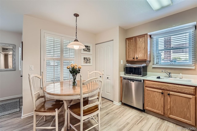 1648 S Cole St Unit A2, Lakewood, CO 80228 - kitchen with stainless steel appliances, a sink, light wood-type flooring, light countertops, and hanging light fixtures