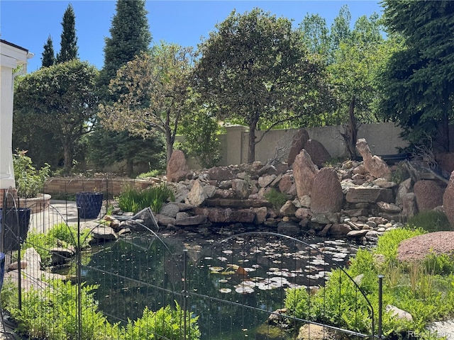 view of yard featuring a garden pond and fence