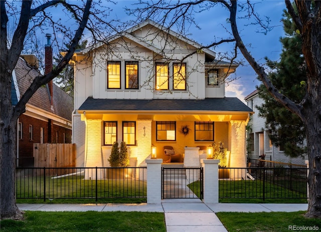 view of front of house featuring covered porch, brick siding, a yard, a fenced front yard, and board and batten siding