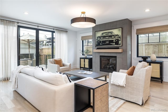 living area featuring a fireplace, light wood-style flooring, baseboards, and recessed lighting