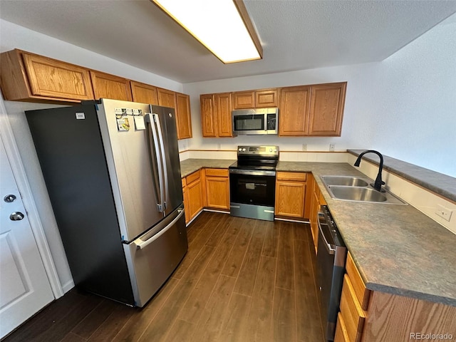 15555 E 40th Ave Unit 11, Denver, CO 80239 - kitchen featuring appliances with stainless steel finishes, a peninsula, dark wood-type flooring, and brown cabinetry