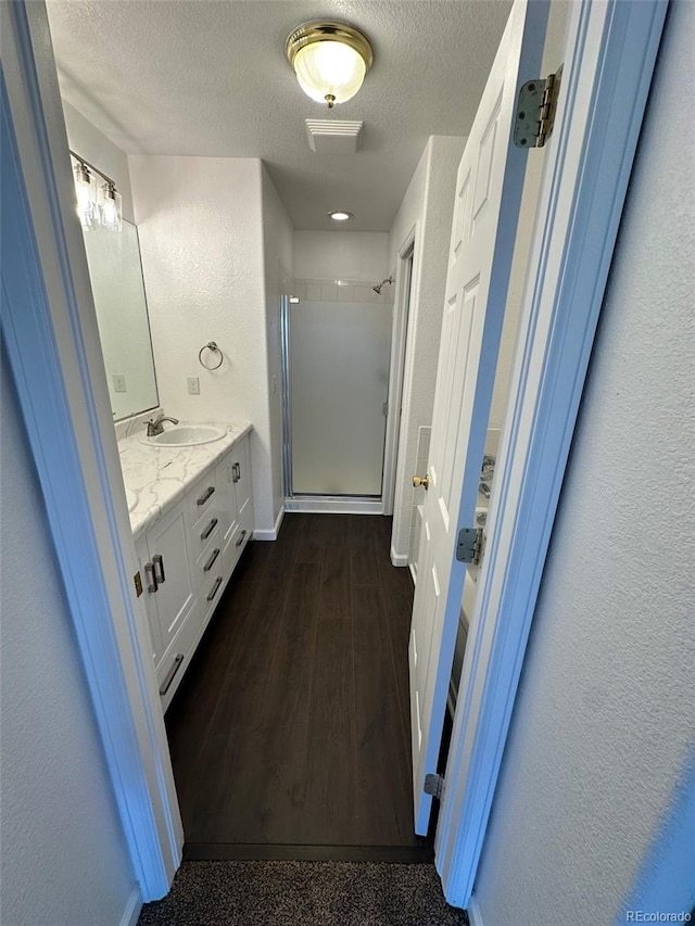 15555 E 40th Ave Unit 11, Denver, CO 80239 - full bath with a shower stall, vanity, a textured ceiling, and wood finished floors