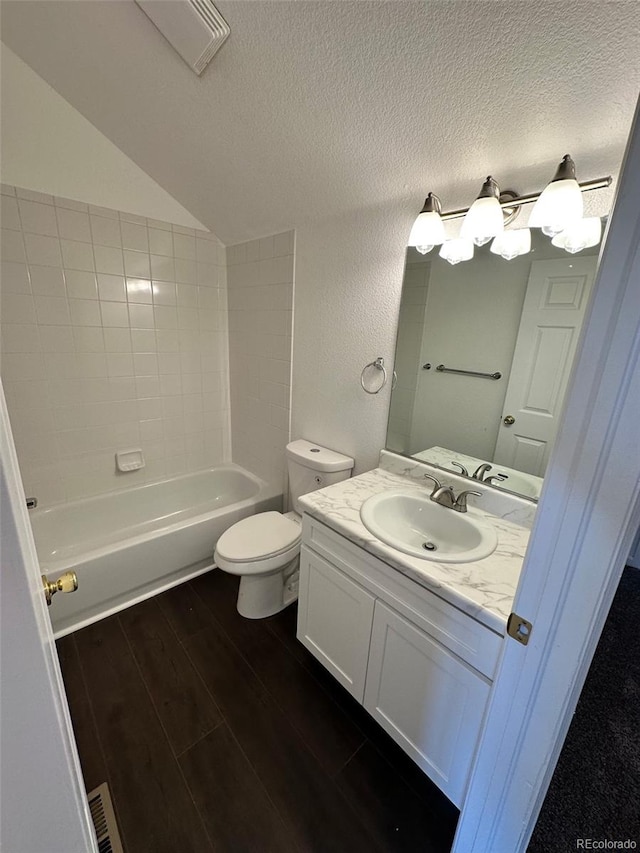 15555 E 40th Ave Unit 11, Denver, CO 80239 - bathroom featuring vaulted ceiling, vanity, wood finished floors, a textured ceiling, and washtub / shower combination