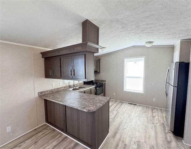 kitchen featuring dark brown cabinetry, freestanding refrigerator, a textured ceiling, light wood-type flooring, and gas stove