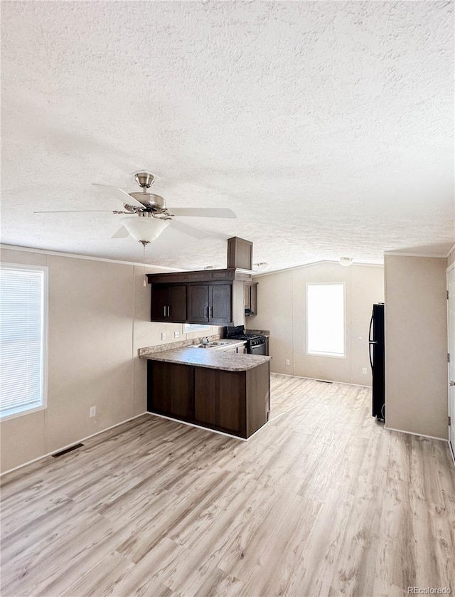 kitchen with a peninsula, a ceiling fan, visible vents, light wood-style floors, and dark brown cabinets