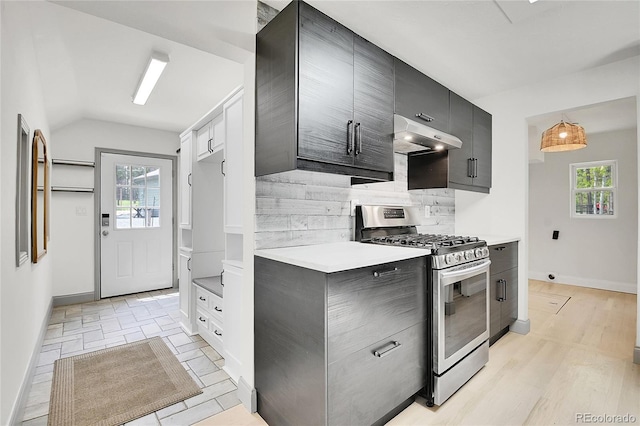 10887 Goodheart Ave, Conifer, CO 80433 - kitchen featuring stainless steel range with gas cooktop, under cabinet range hood, backsplash, light countertops, and vaulted ceiling